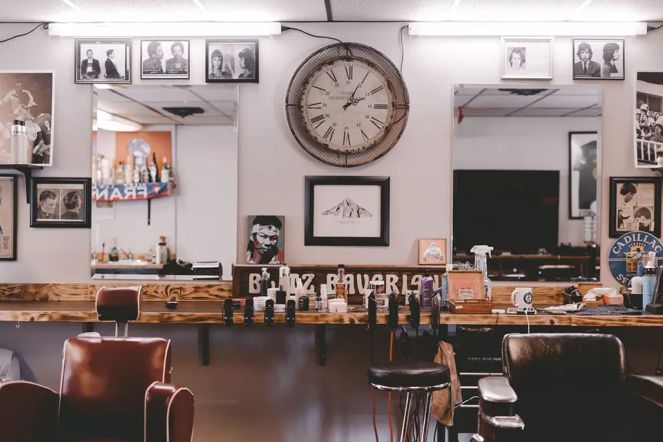 A barbershop with leather chairs, framed prints and a wall clock